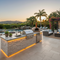 Outdoor Kitchen Islands for Backyard Cooking - deluxe outdoor kitchen island with grill, sink, refrigerator, pizza oven and stone veneer siding on the edge of a travertine patio with a luxurious oasis backyard